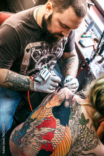 the process of creating a tattoo on the back of a girl © sushytska