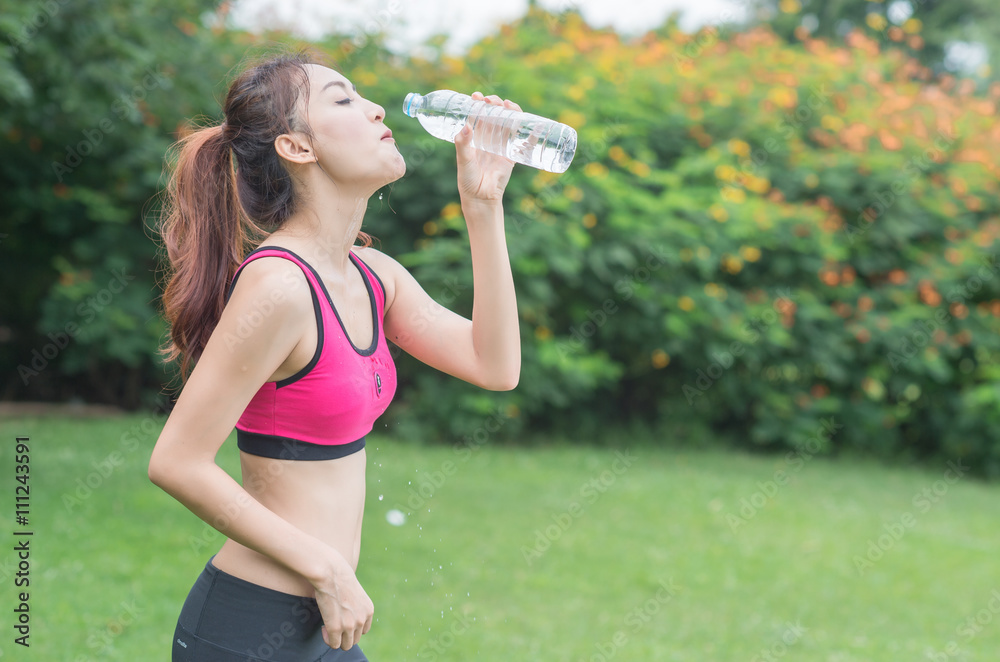 young attractive woman drinking water from plastic bottle in the park young attractive woman drinking water from plastic bottle in the park