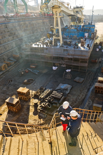 Dock workers in dry dock.
