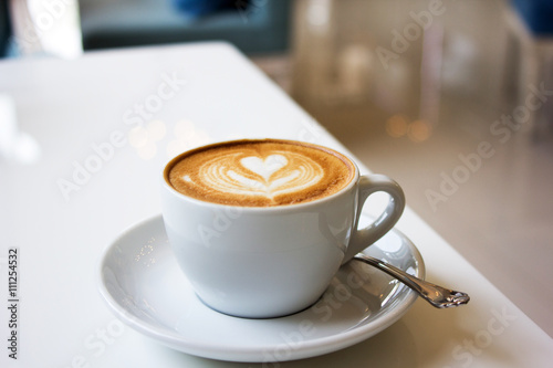 white cups of Cappuccino coffee with froth heart shaped on table