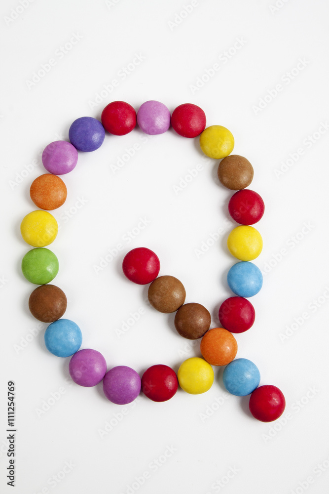La lettera Q formata da coloratissimi confetti di cioccolato.
