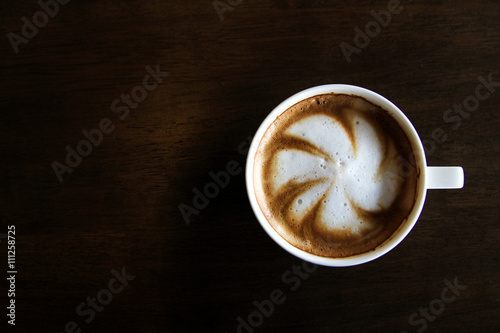 Cup of cappuccino art coffee with froth shape plumeria and woode