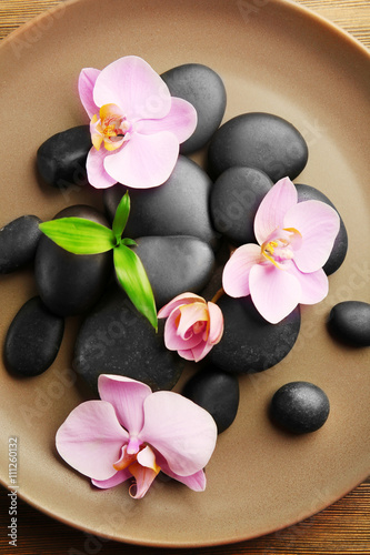 Spa stones and orchid flowers in round plate  top view