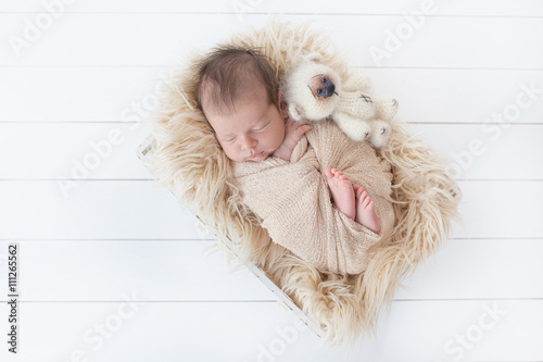 sleeping newborn baby in a basket with a toy