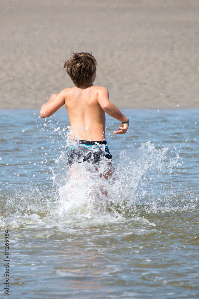 Junge sprintet durchs Meer Junge sprintet durchs Meer
