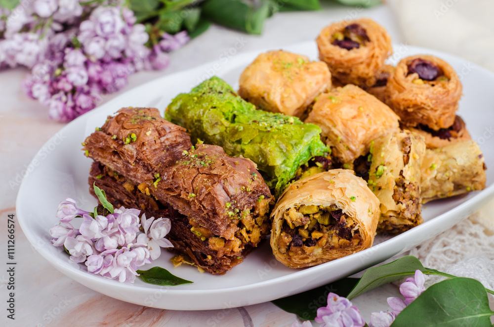 Mixed baklava in white plate on marble background. Ramadan food, turkish arabian cuisine. Selective focus Mixed baklava in white plate on marble background. Ramadan food, turkish arabian cuisine. Selective focus