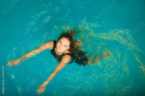 Woman floating relaxing in swimming pool water.