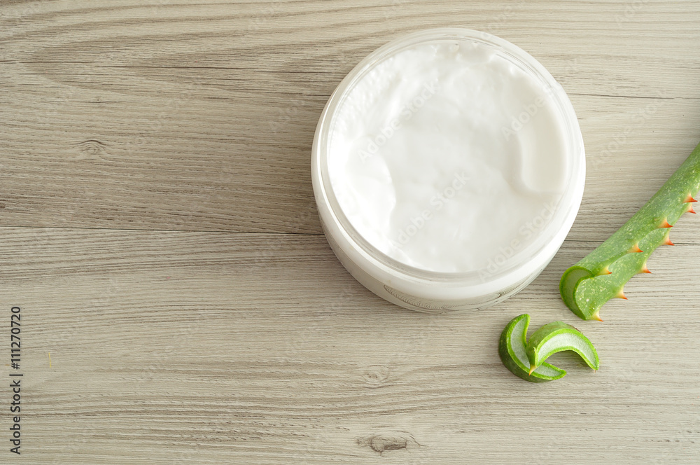 White beauty cream in a jar displayed with aloe Vera on a wooden background White beauty cream in a jar displayed with aloe Vera on a wooden background