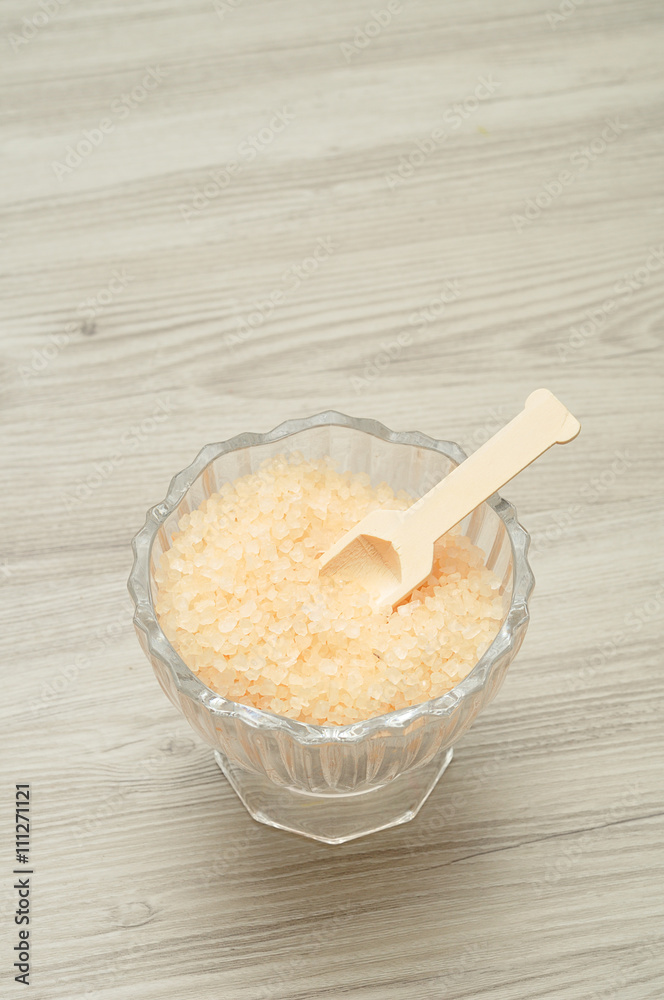 A bowl of bath salt displayed with a wooden spoon A bowl of bath salt displayed with a wooden spoon