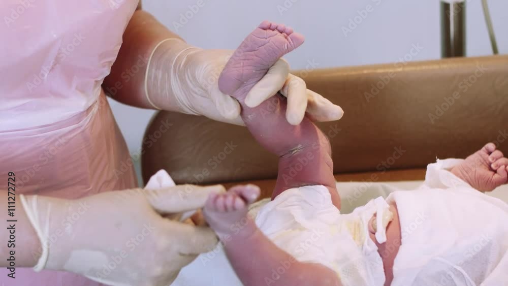 Nurse in sterile gloves put on disposable socks on newborn baby in diapers after birth. Maternity hospital. Nurse in sterile gloves put on disposable socks on newborn baby in diapers after birth. Maternity hospital.