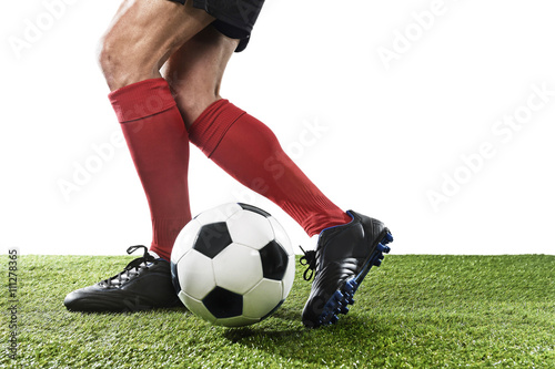football player in red socks and black shoes running and dribbling with the ball playing on grass