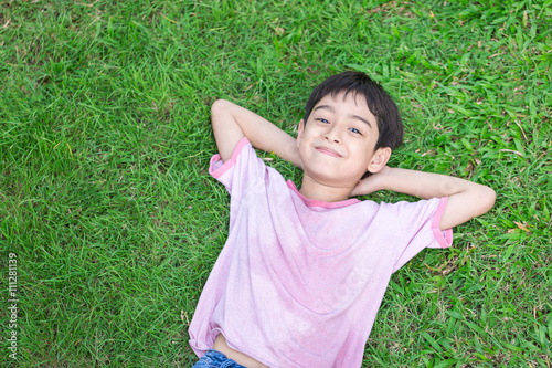 Little boy lay down on the grass with smile face