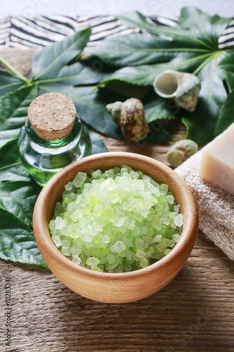 Bowl of green sea salt, bottle of essential oil and bars of soap