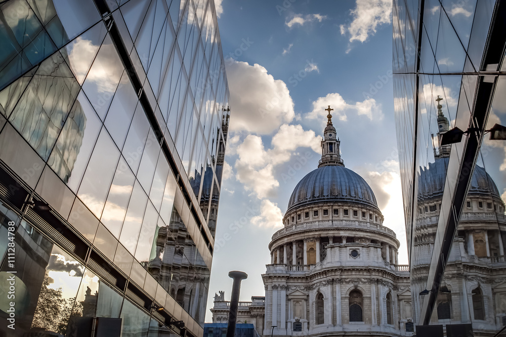 St Paul’s cathedral seen from a narrow alley enclosed by glass buildings on a cloudy day in summer
