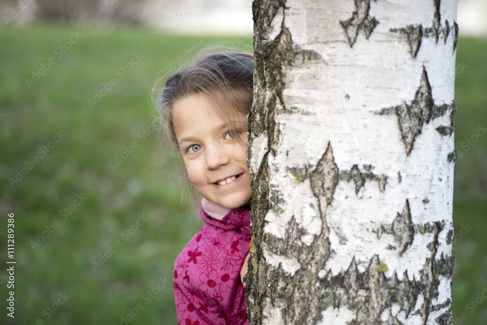 cheerful girl hiding behind birch stem by spring cheerful girl hiding behind birch stem by spring