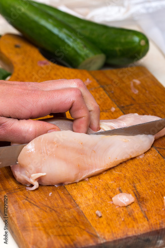 Woman hand cuting chicken meat on the board