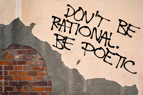 Handwritten graffiti Don't Be Rational. Be poetic sprayed on wall, anarchist aesthetics. Appeal to appreciate open-minded creativity and thinking outside of the box instead of small-minded pragmatism