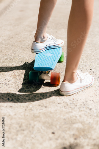 Young girl in sneakers on skateboard.