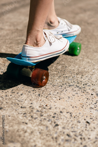 Young girl in sneakers on skateboard.