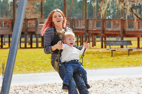 Mother and daughter in a swing at the park photo