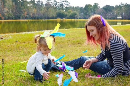 Mother and daughter playing with feathers in park photo