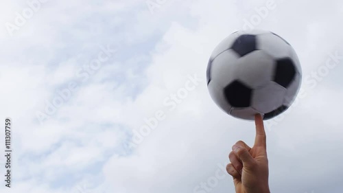 4K Football or soccer ball spinning on a finger against a sky background, in slow motion, with space for text