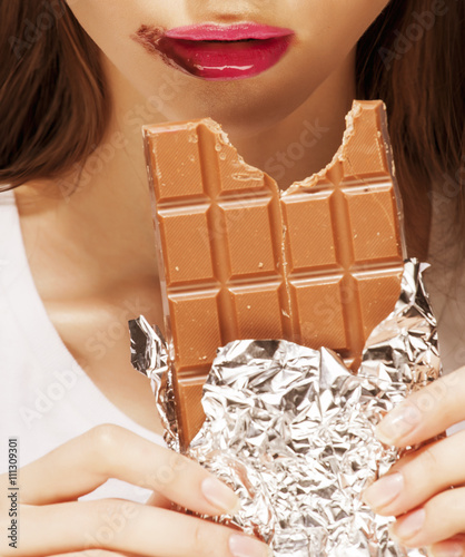 woman eating chocolate, close up hands with manicure french nails holding candy, beautiful fingers photo