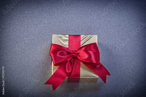 Present box with red ribbon on grey background holidays concept