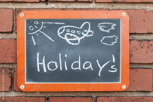 Tafel an einer Ziegelwand mit Text / Tafel an einer Ziegelwand mit Text Holiday`s.