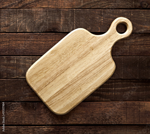 Cutting board on dark wooden table, top view