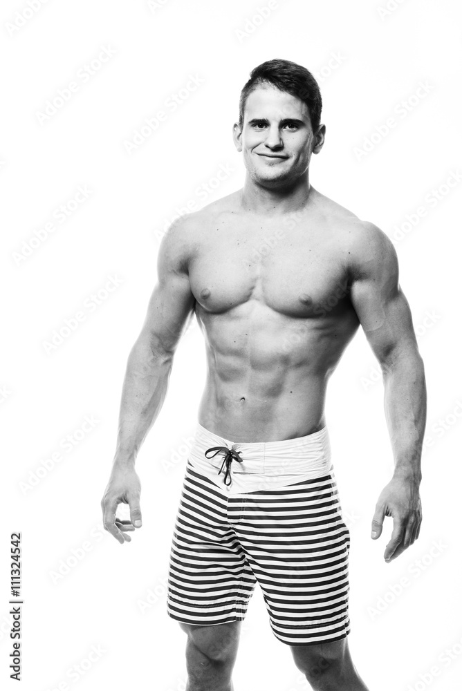 Fototapeta premium Sexy athletic man showing muscular body and sixpack abs, isolated over white background. Strong male nacked torso. Monochrome photo.