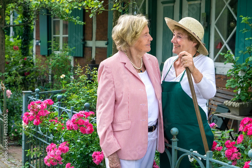 Two Senior Women Talking Together in Garden. photo