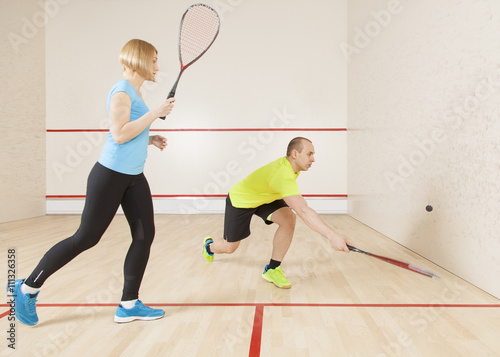 young caucasian man and woman playing squash.