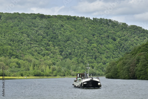 Péniche naviguant en toute tranquillité dans la Meuse entre paysage de collines et forêts à Hastière 