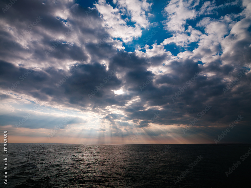 image of ocean and sun beams through clouds.