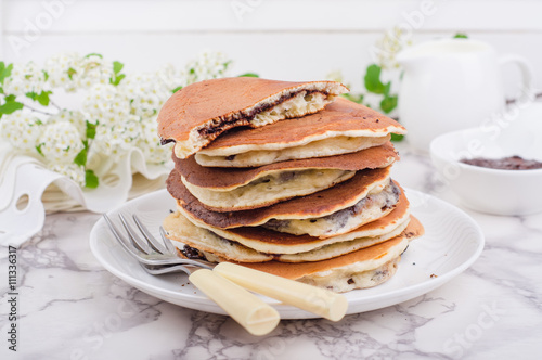 Stuffed chocolate pancakes on n vintage slate chalk board background with flowers and coffee cup. Selective focus