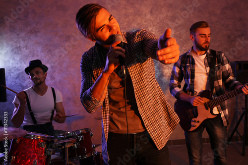 Musicians playing musical instruments and singing songs in a studio photo