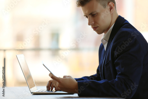 Man using laptop and smart ...