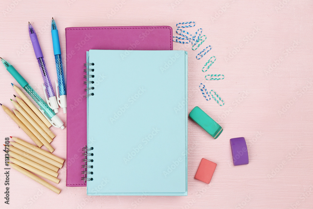 Office set with notebooks, colored pens and pencils on pink background