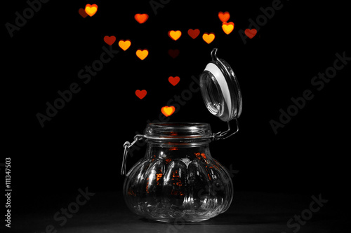 Miracle of love from glass jar on black background photo