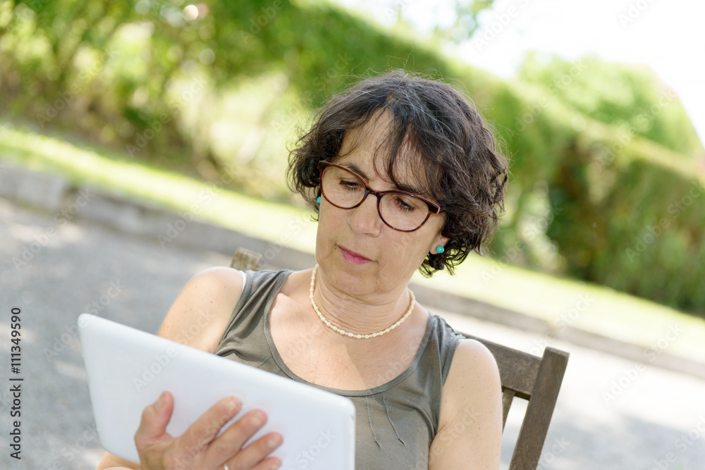 Obraz premium charming woman with a tablet in her garden