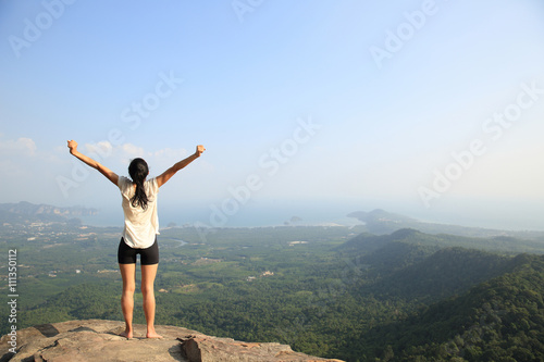 young freedom woman open arms on mountain peak
