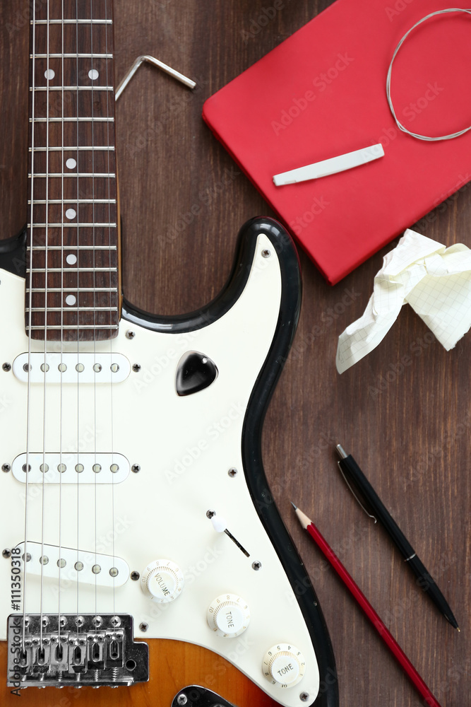 Fototapeta premium Guitar with notebook on wooden table closeup