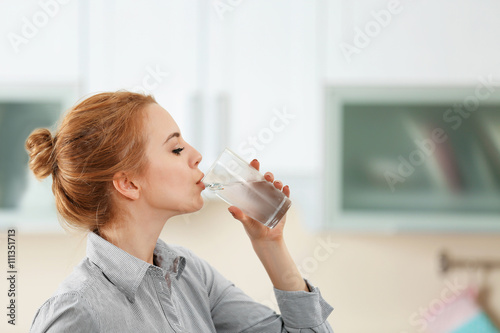 Young woman in the kitchen drinking water