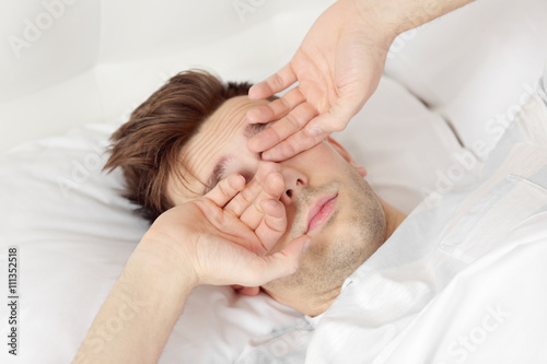 Young man rubbing his eyes ...
