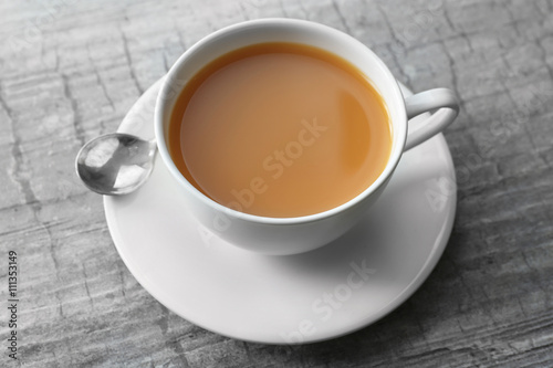 Cup of tea with milk on wooden background