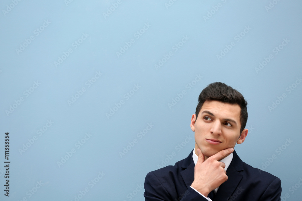 Attractive young man in a suit against light blue wall Attractive young man in a suit against light blue wall
