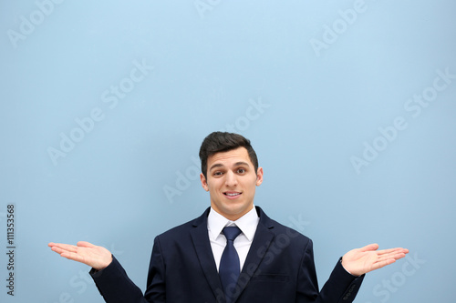 Attractive young man in a suit against light blue wall