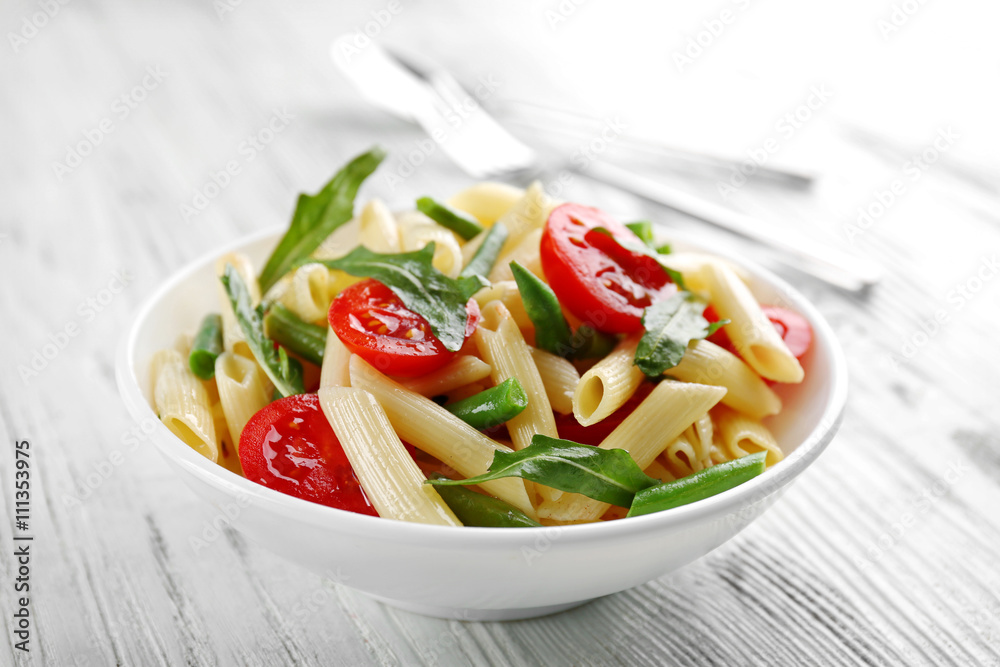 Boiled penne pasta with tomatoes, French bean and arugula on white plate Boiled penne pasta with tomatoes, French bean and arugula on white plate