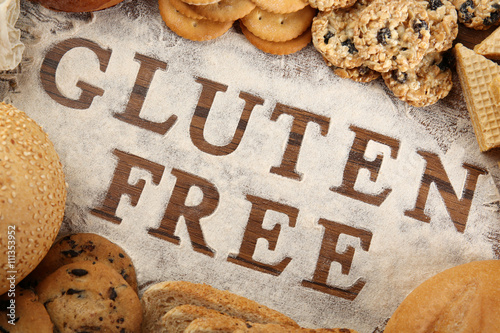 Foto Text GLUTEN FREE with bakery products and flour on wooden surface closeup